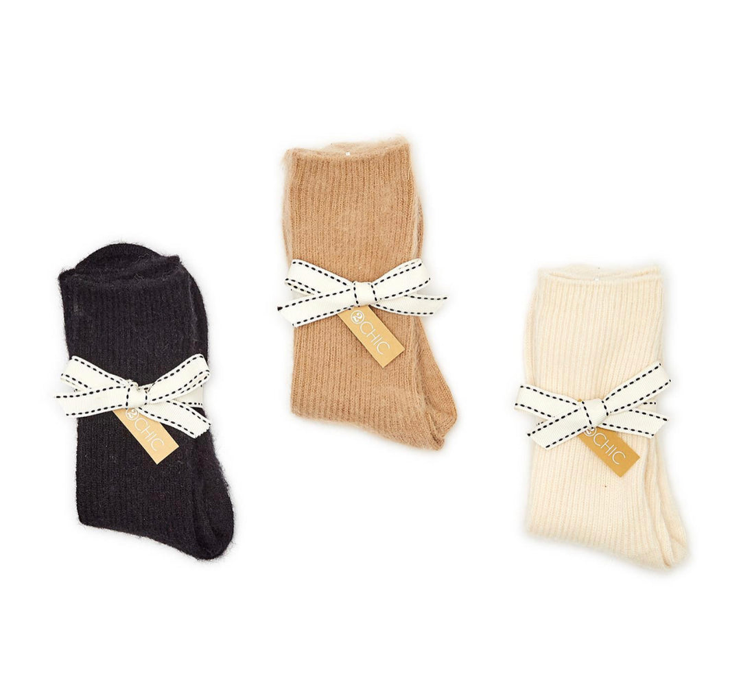Three pairs of cashmere socks in black, brown, and cream, each with "SO CHIC" tag. Available in sizes S, M, L.