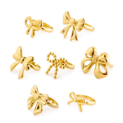 Set of seven gold bow rings, including Forget Me Not and an adjustable ring. Available in sizes 5-9.