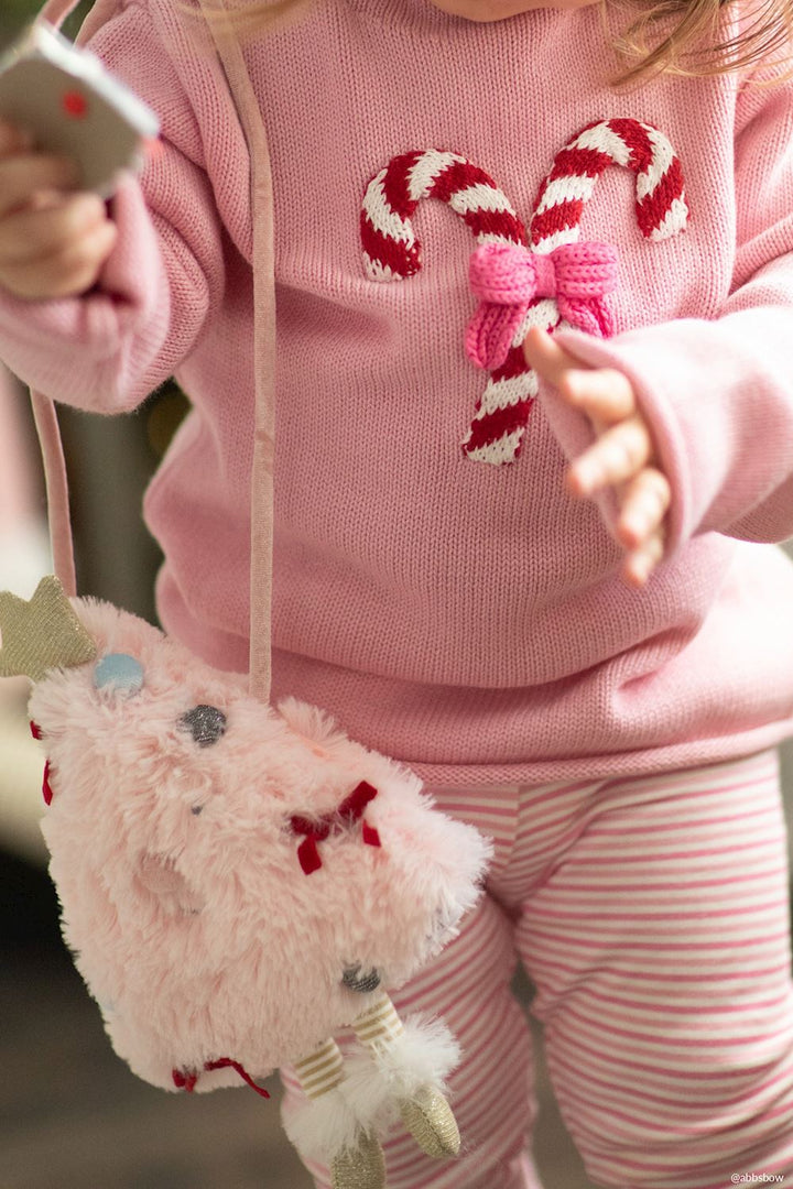 Fluffy pink Christmas tree-shaped plush purse with ribbon details and dangling legs.