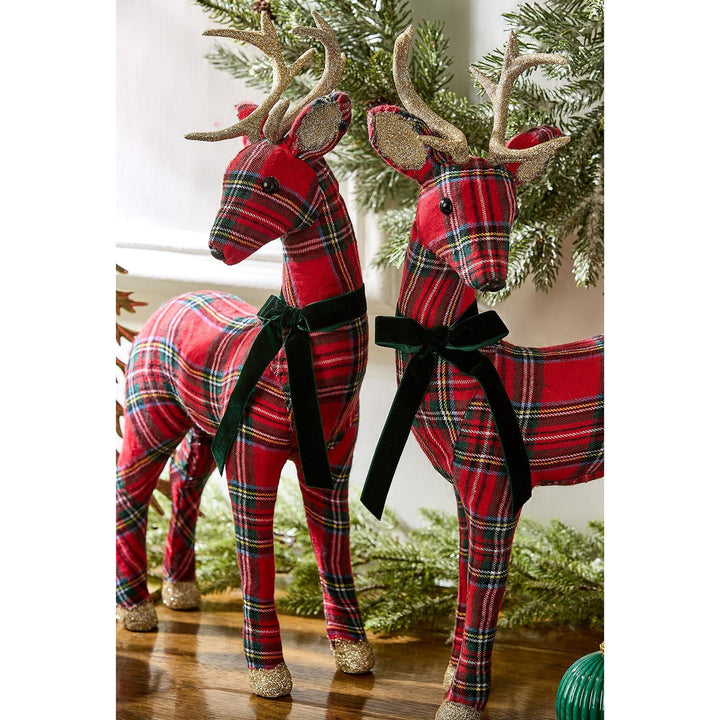 Two red tartan reindeer figurines with green velvet bows and glittery gold antlers and hooves.