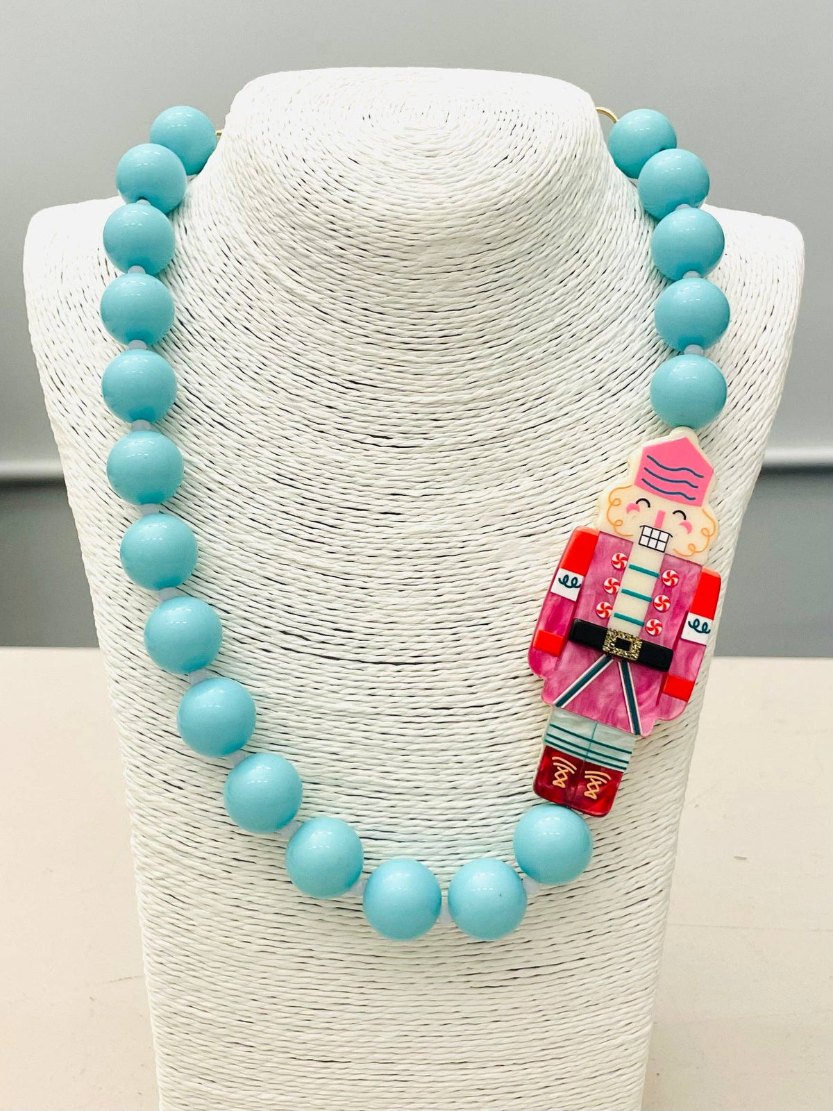 Beaded Nutcracker Necklace (blue/pink) BNK1214 features large turquoise beads and a red, pink, and blue Nutcracker pendant. Available in multiple sizes.