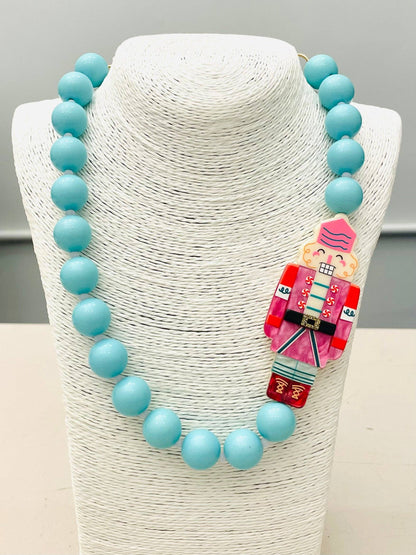 Beaded Nutcracker Necklace (blue/pink) BNK1214 features large turquoise beads and a red, pink, and blue Nutcracker pendant. Available in multiple sizes.