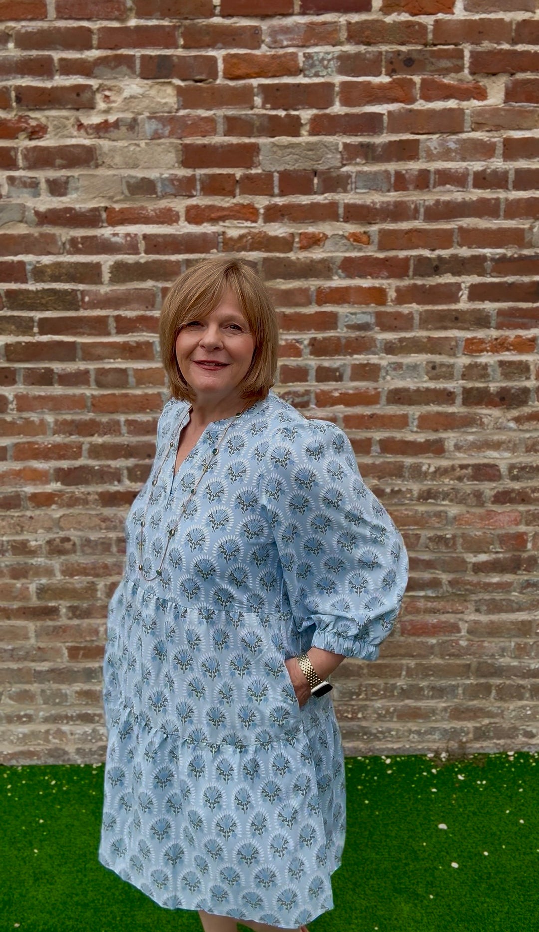 Light blue patterned V-neck Cooper Botanical Blooms Dress with tiered skirt and pockets. Available in sizes XS-XL.