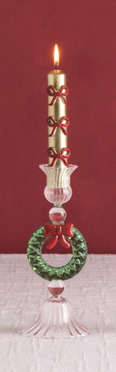 Burning gold Christmas Mini Taper Candle with a red bow in a glass holder with a green wreath and red bow accent.