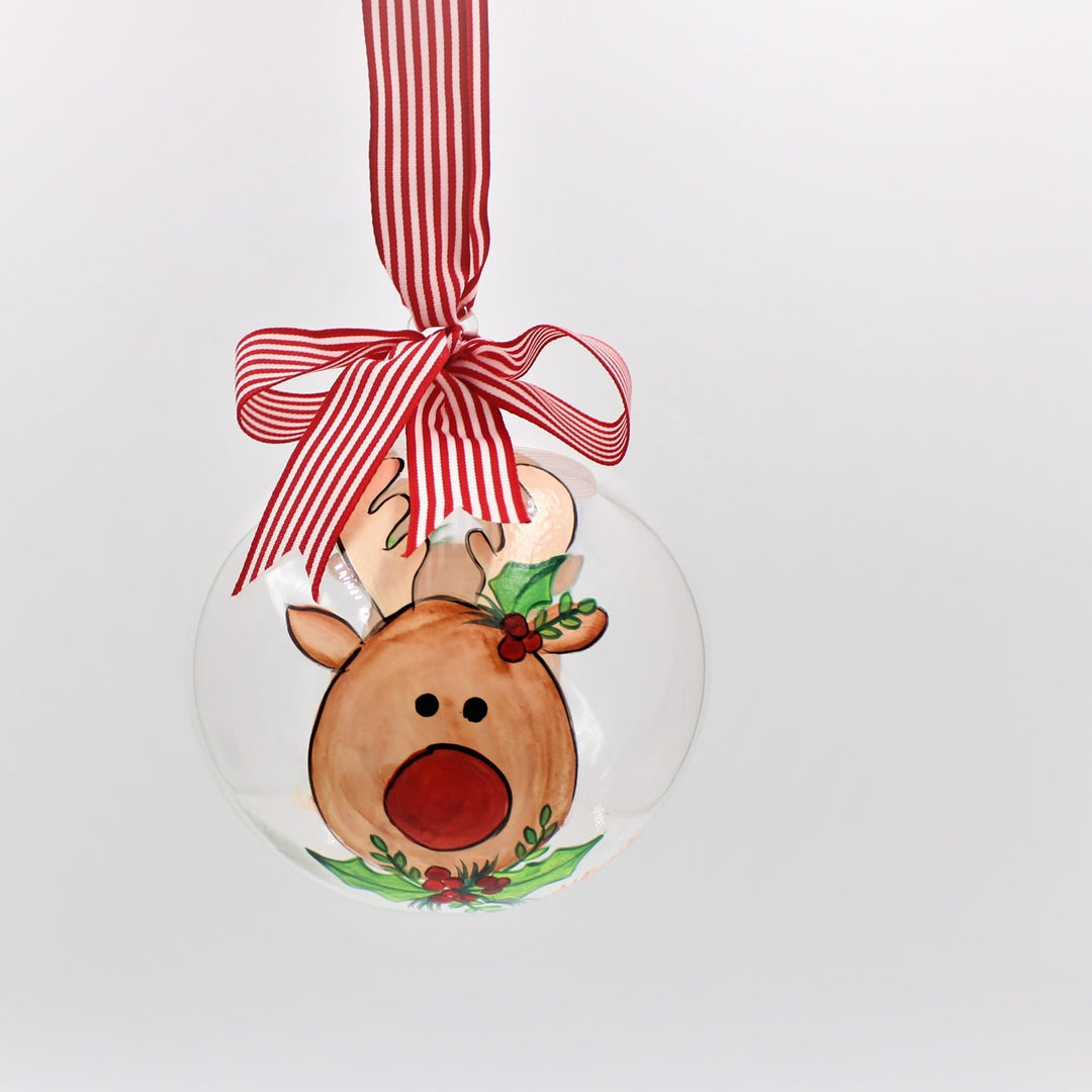 Hand painted glass reindeer ornament with holly on a clear globe, hanging from a red and white striped ribbon bow.