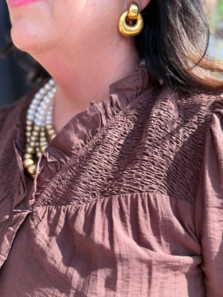 Brown textured blouse with elegant detailing, available in sizes XS–XL.