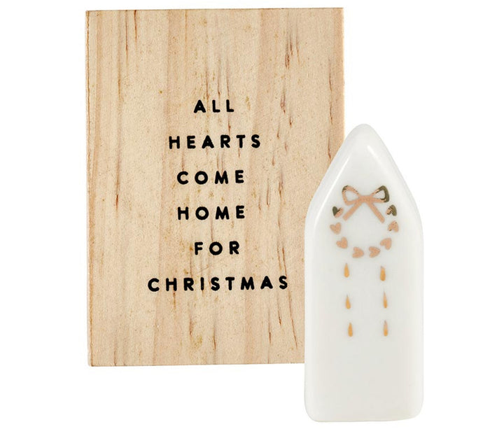 Ceramic figurine pine wood box with “All hearts come home for Christmas” wooden sign and white ceramic house-shaped figurine with gold heart wreath design.