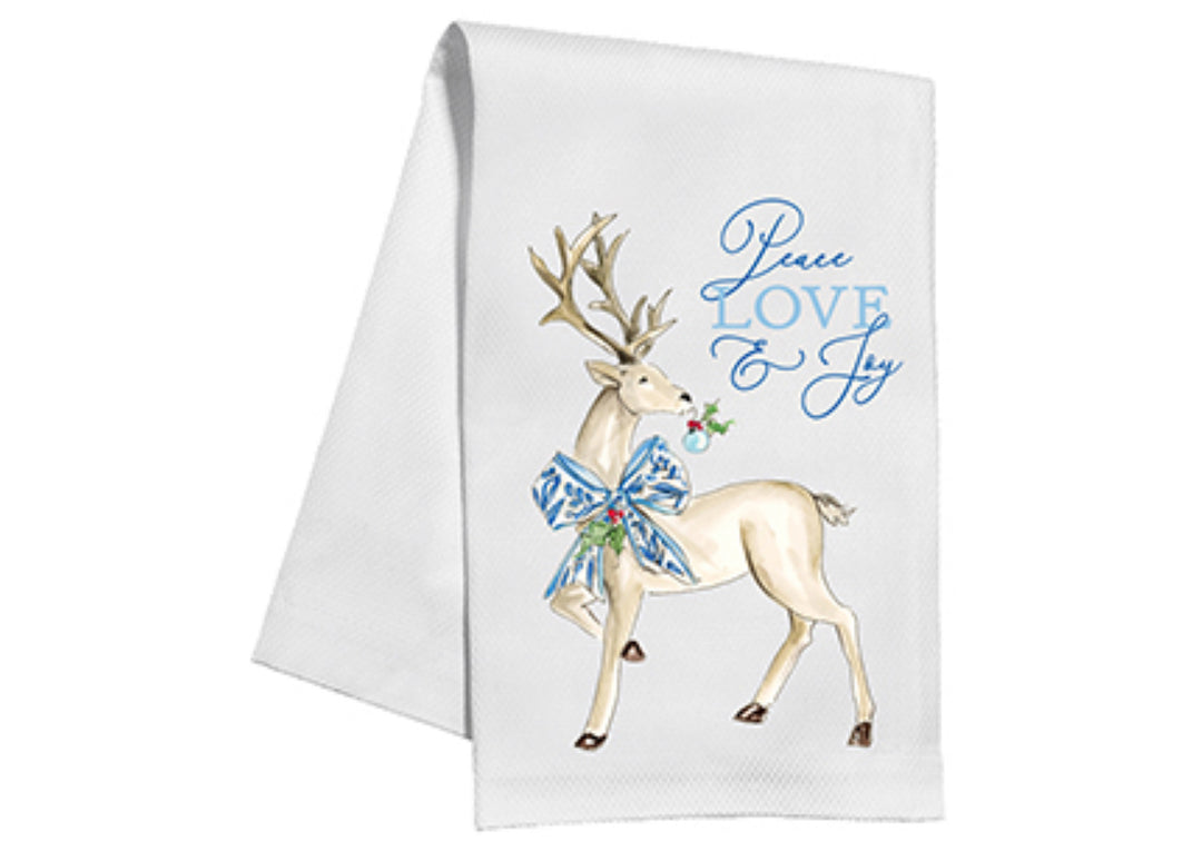 White kitchen towel with elegant reindeer illustration; features large antlers, blue patterned bow, and small ornament. Text: "Peace, Love &amp; Joy" in blue cursive. 100% cotton, machine washable. Available sizes: 18x28 inches.