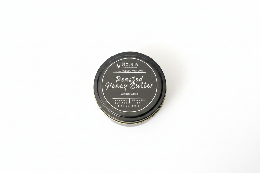 Small round tin labeled "Roasted Honey Butter" Wickless Candle, 5.75 oz size, No. 948, made from coconut soy wax with a black lid featuring white decorative text and product details.