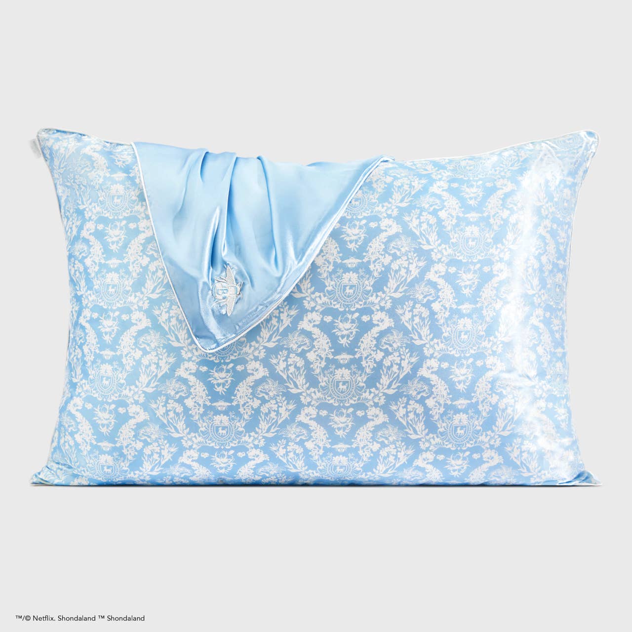 Blue and white floral satin pillowcase with folded light blue corner, embroidered crest. Available in standard and king sizes.