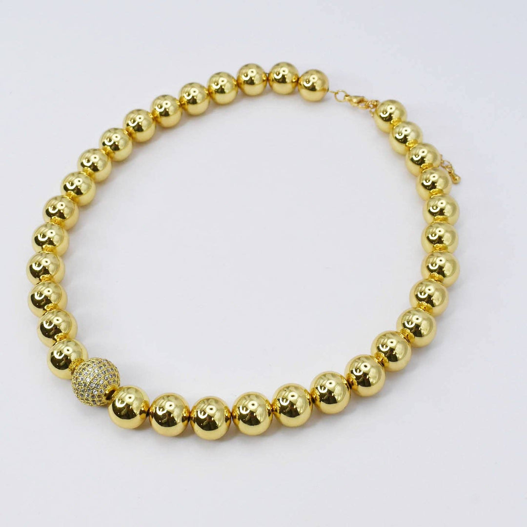 The Golden Pixie Necklace: 16-inch strand of shiny gold beads, one larger textured bead with crystal accents.