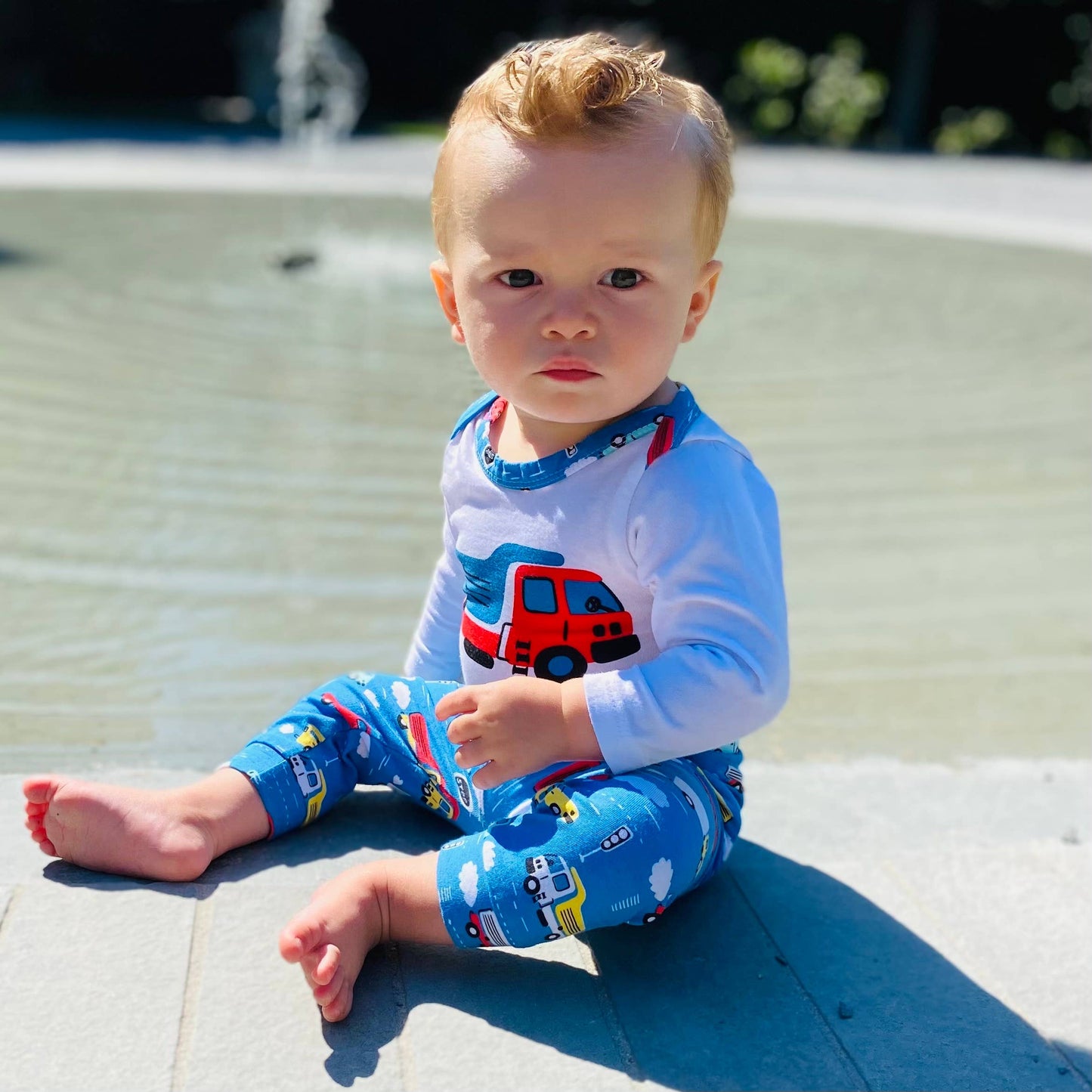 Little boy modeling onesie and pants sitting looking off to the left