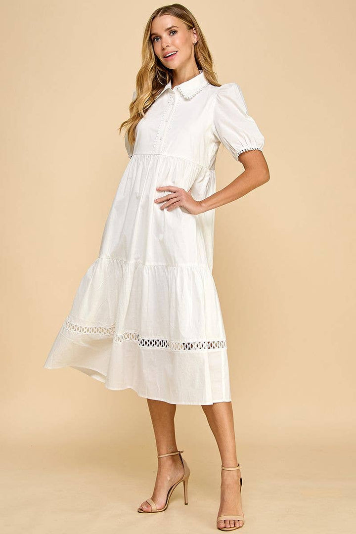 White button-up collared midi dress with contrast trim, short sleeves, and tiered skirt. Available in sizes XS–XL.