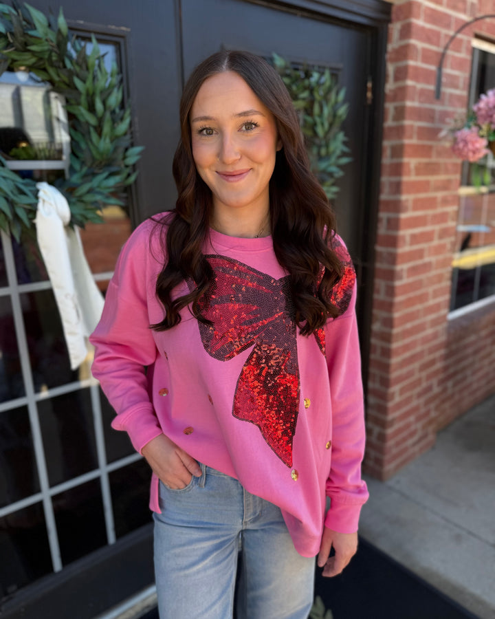 Pink relaxed fit Sequin Bow Sweatshirt with a red sequined bow graphic. Available in all sizes.