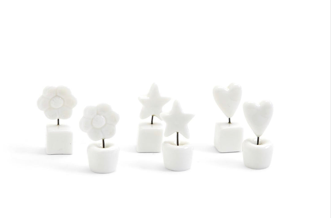Six small white ceramic holders with metal stems topped by white flowers, stars, or hearts; available in one compact size.