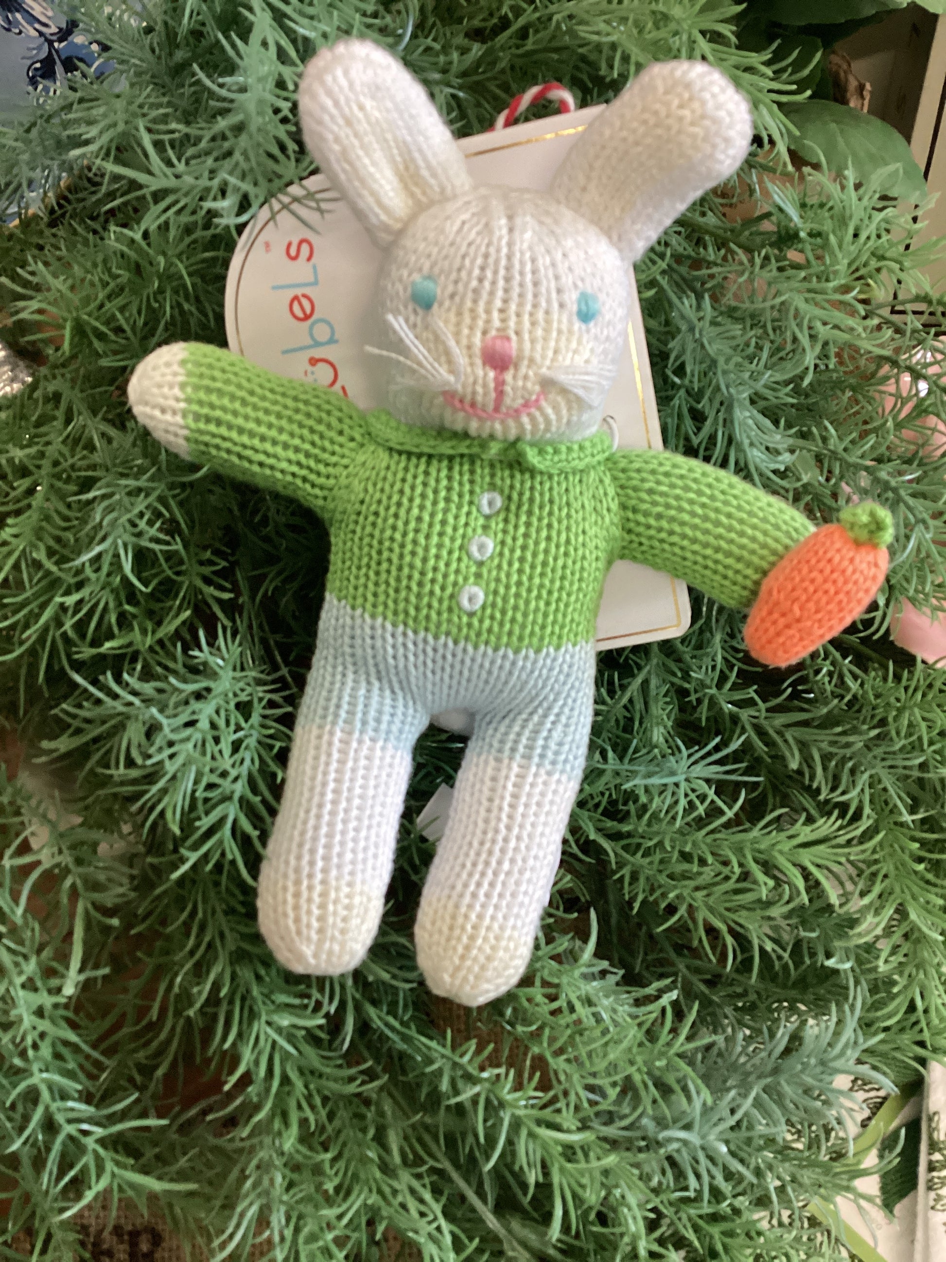 The Boy Bunny Rattle: knitted, soft white fur, green sweater, blue pants, orange carrot in hand. Sizes: small, medium.