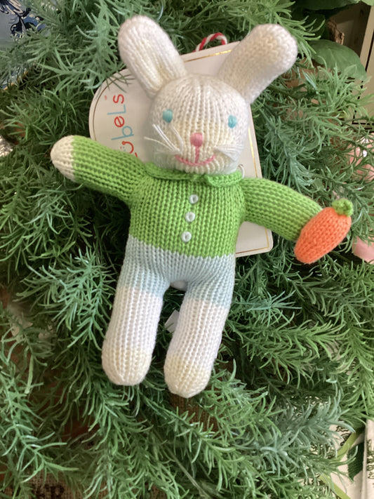 The Boy Bunny Rattle: knitted, soft white fur, green sweater, blue pants, orange carrot in hand. Sizes: small, medium.