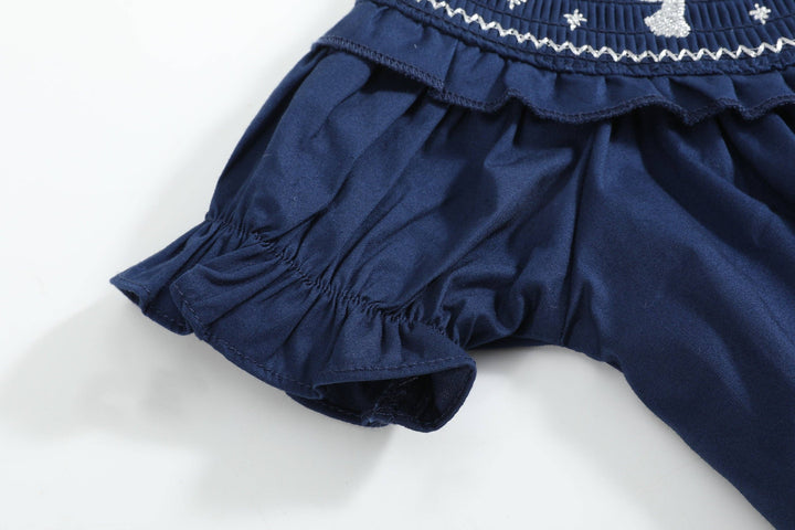 Navy blue ruffled sleeve and part of Blue Nativity Smocked Ruffle Romper in 2T, with white stitching and cat design on bodice.