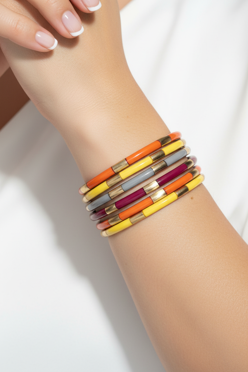 The Autumn Veda Stack features colorful segmented bangle bracelets in yellow, orange, red, cream, and gold tones. Available in sizes small, medium, and large.