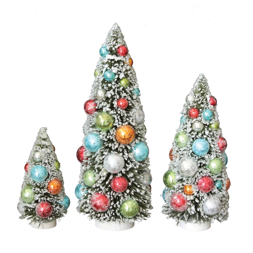 Three flocked bottle brush trees with ornaments in varying heights.