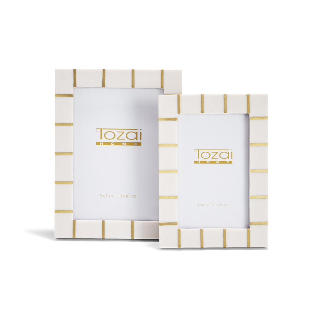 White rectangular resin photo frames with gold horizontal stripes from the Brass Lines collection, available in two sizes. Each frame displays the "Tozai Home" logo and frame dimensions.