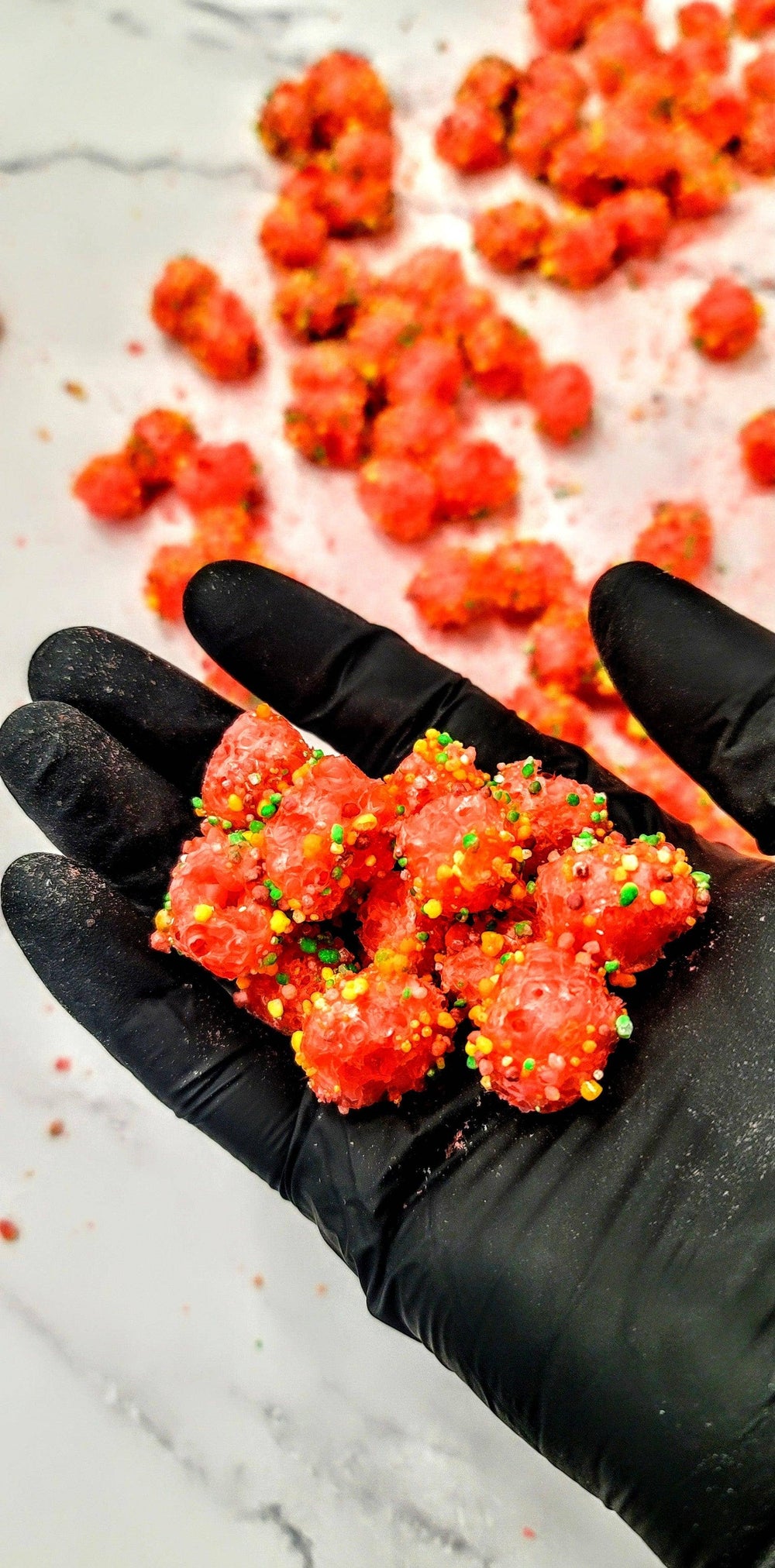 Bright red, round Original Crunchy Clusters: Singles, coated in colorful sprinkles. Available in small and large sizes.