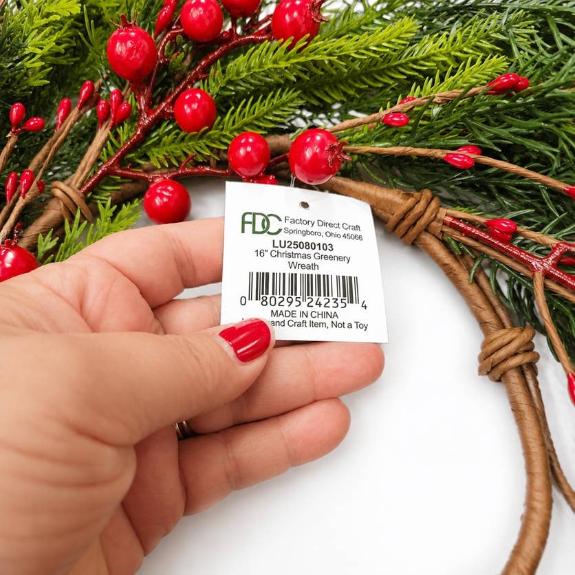16″ Fir Pine and Red Berries Candle Ring or Wreath in green and red, with lush Christmas greenery and vibrant red berries. The tag reads, “16′’ Christmas Greenery Wreath, Made in China, Not a Toy.” Available in 16″ size.