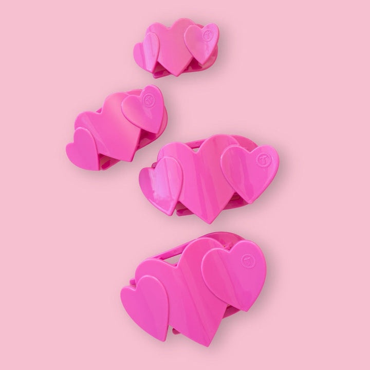Set of four pink heart-shaped flat clips in small, medium, and large sizes; bendable and suitable for all hair types.