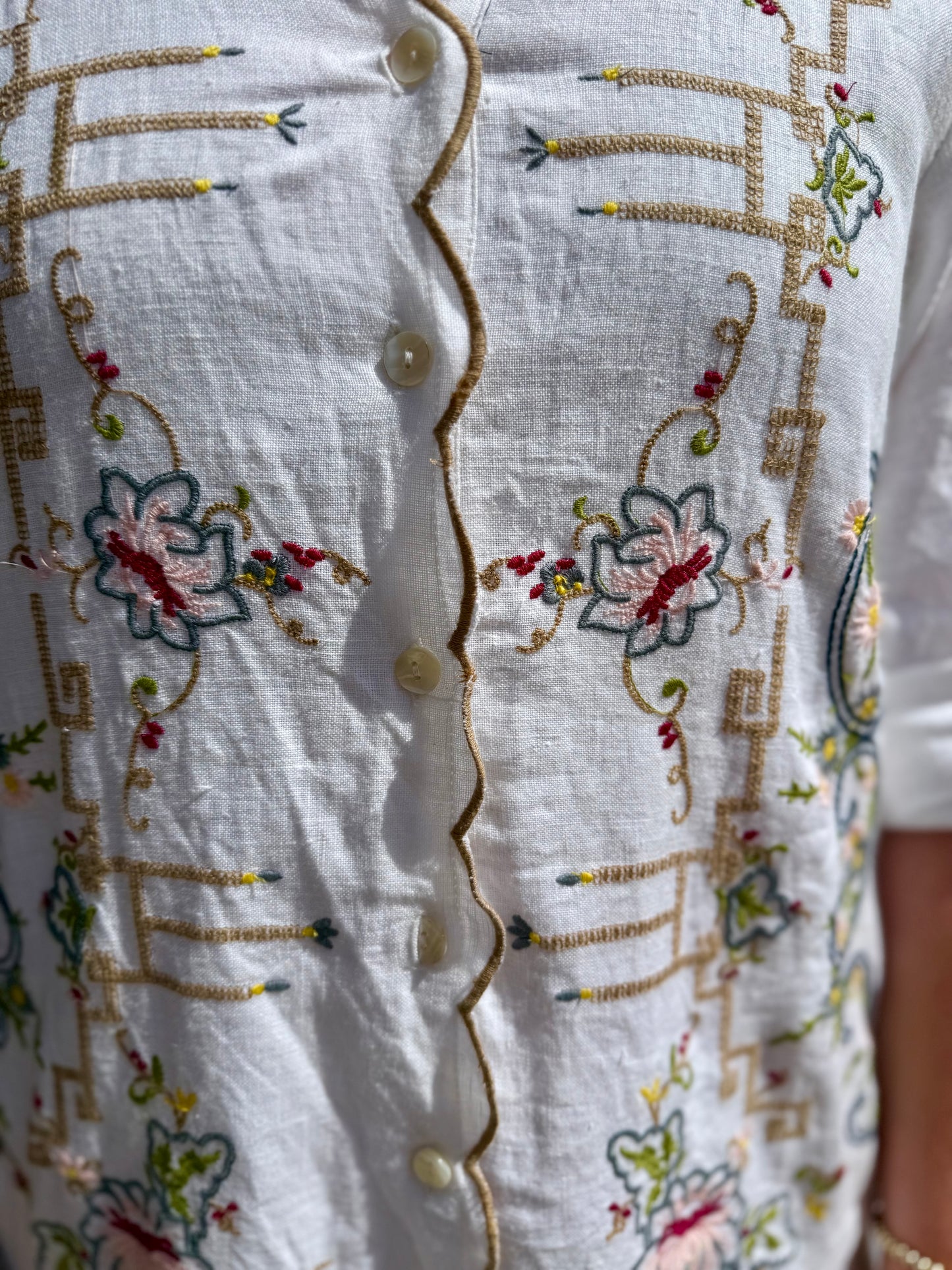 White Table Linens Dress with cream buttons, vibrant floral embroidery, geometric accents; lightweight. Sizes: XS-XL.