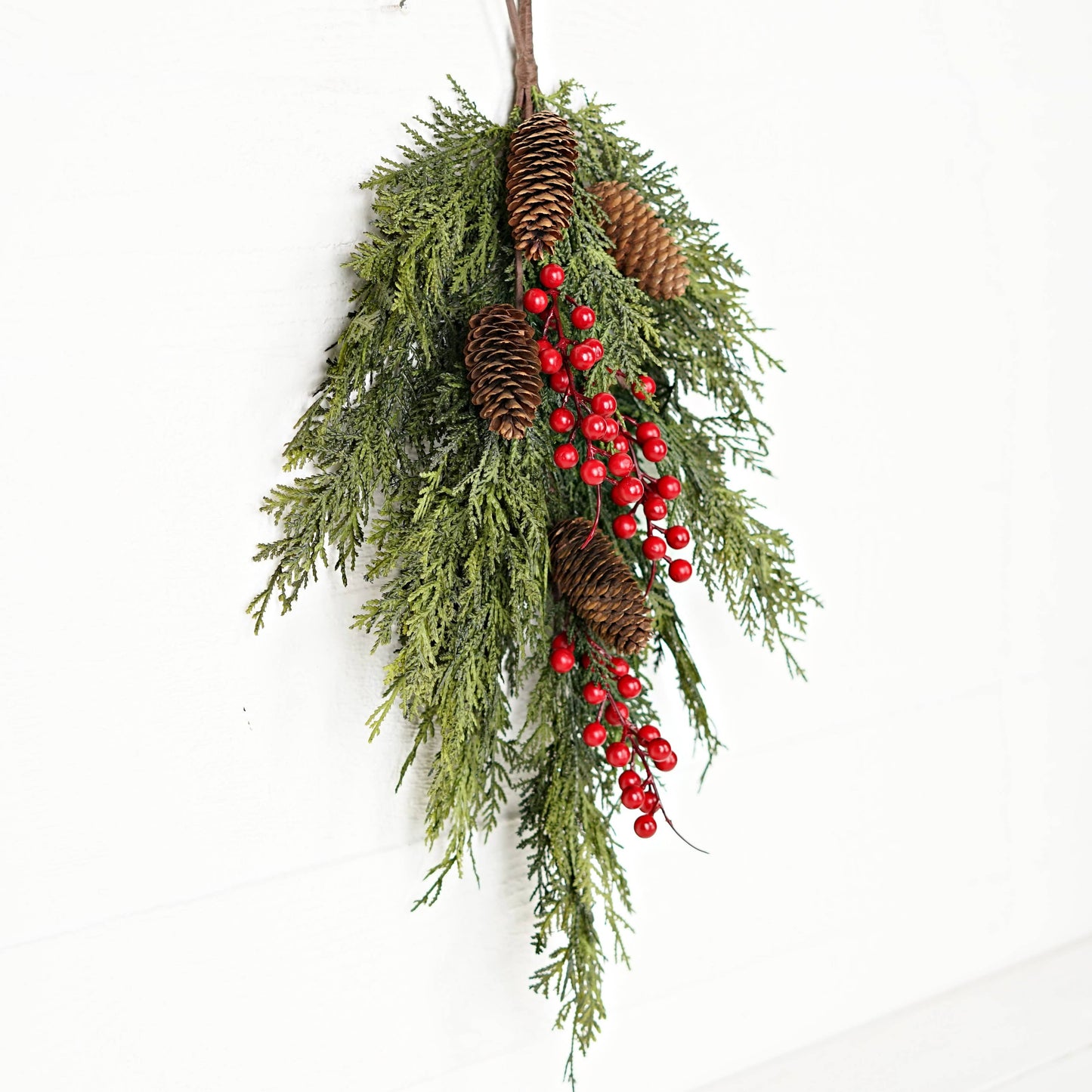 Festive 26inL x 16inW teardrop swag (Product 510053) with real touch mixed cedar branches, pinecones, and red berry clusters.