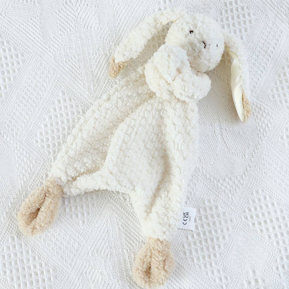 Cream lovey bunny with looped hands holding blanket and knots at corners. Brown tipped ears and feet.