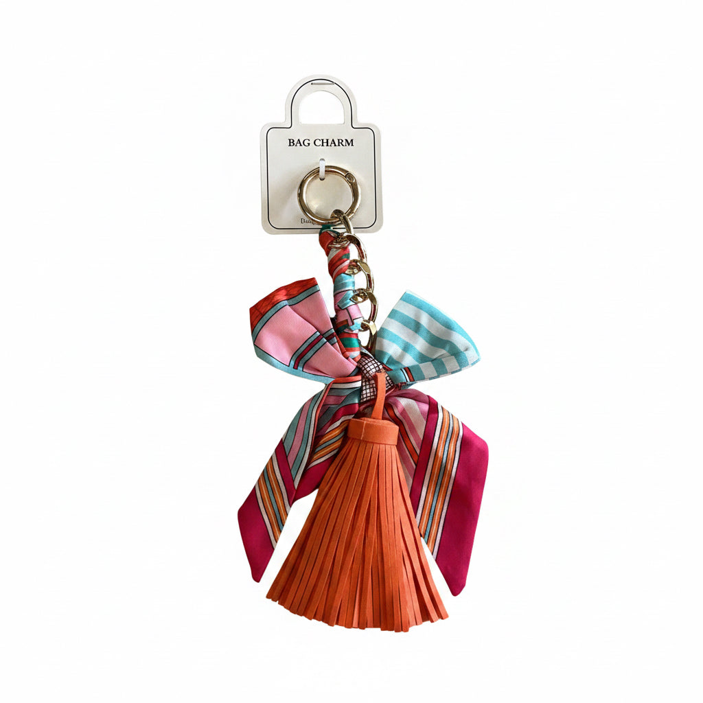 Vibrant orange tassel with pink, blue, and red striped ribbons on a gold-toned ring and a white “BAG CHARM” tag. Available in small and large sizes.