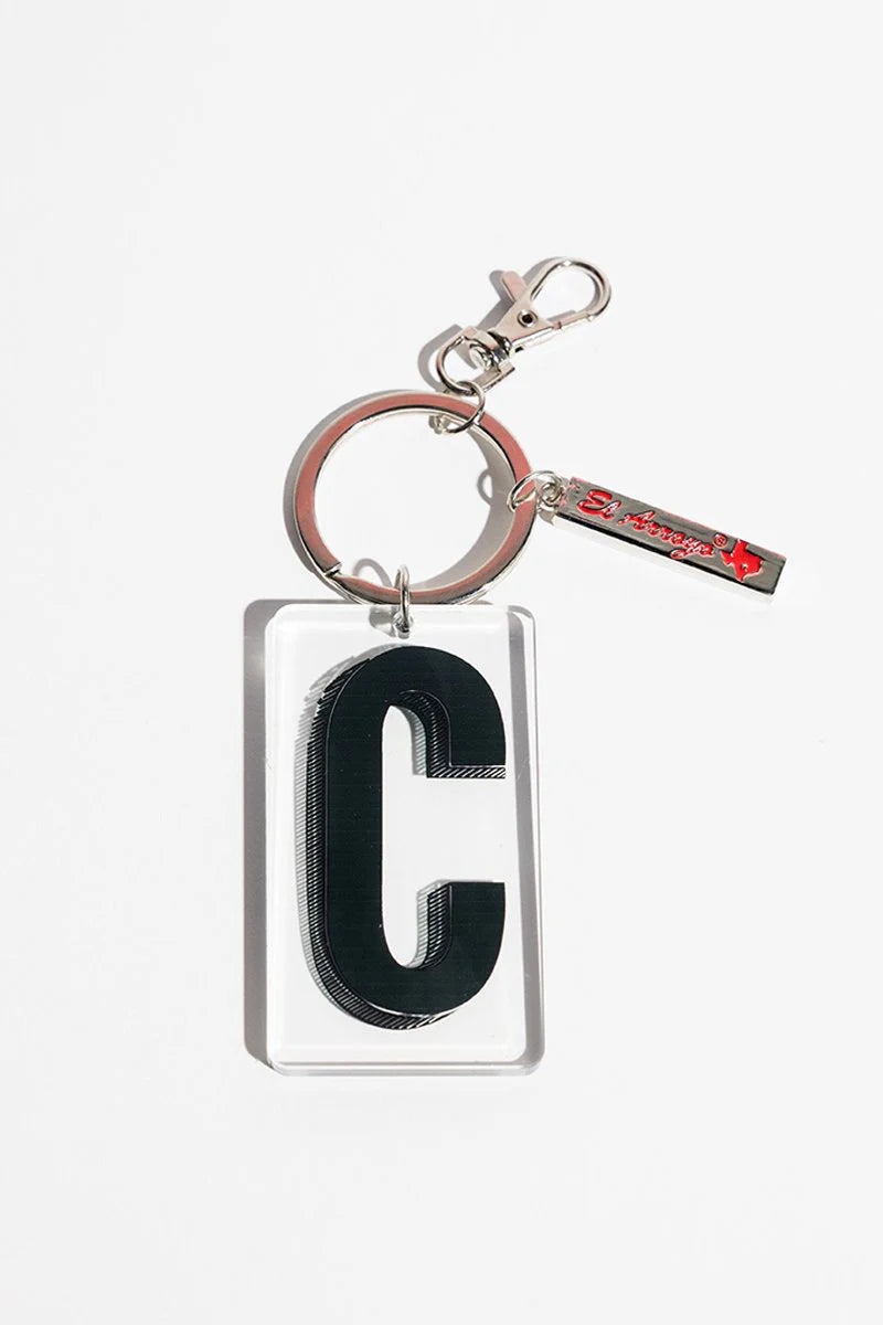 Clear acrylic keychain with bold black “C,” metal ring, clasp, and small red-lettered El Arroyo tag. Sizes: not specified.