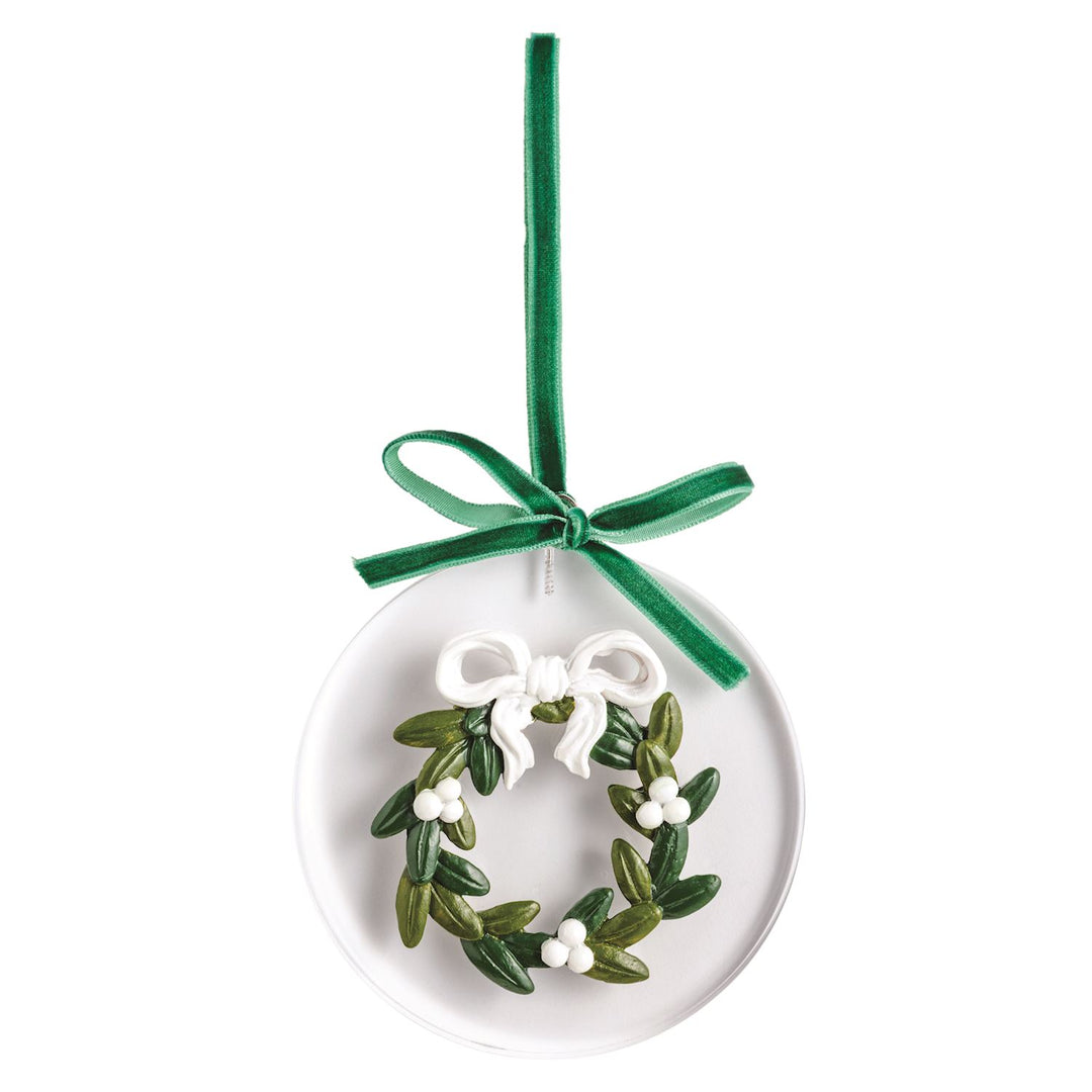 Round white acrylic ornament with a sculpted green wreath, white berries, and a white bow on a green velvet ribbon.