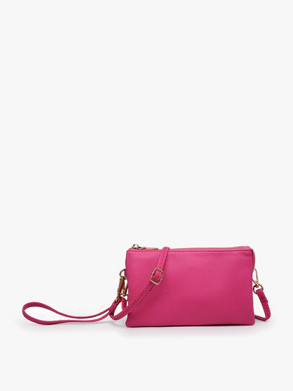 The Riley Crossbody Bag is a small, bright pink vegan leather bag with gold-tone hardware, zippered top, and detachable strap. Sizes: S/M/L.