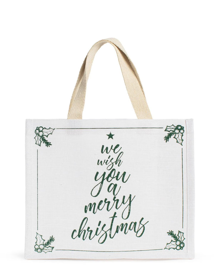We Wish You Gift Tote, an off-white rectangular Christmas gift bag with “we wish you a merry Christmas” green text in a tree shape and corner holly illustrations.