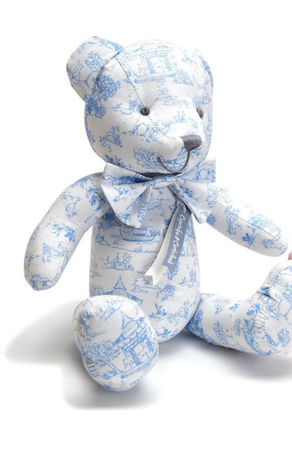 Stuffed teddy bear with white and light blue scenic print, matching bow. Available sizes: small, medium, large.