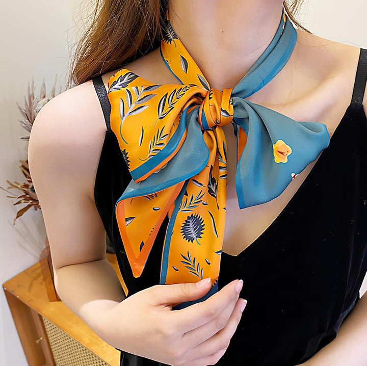 Large silk scarf in yellow and teal floral satin, styled in a bow at the neckline. Available in S, M, and L sizes.