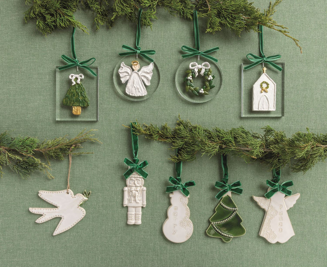 Nine hand-painted acrylic ornament designs: angel, wreath, church, dove, nutcracker, snowman, and trees, suspended by green velvet ribbons.