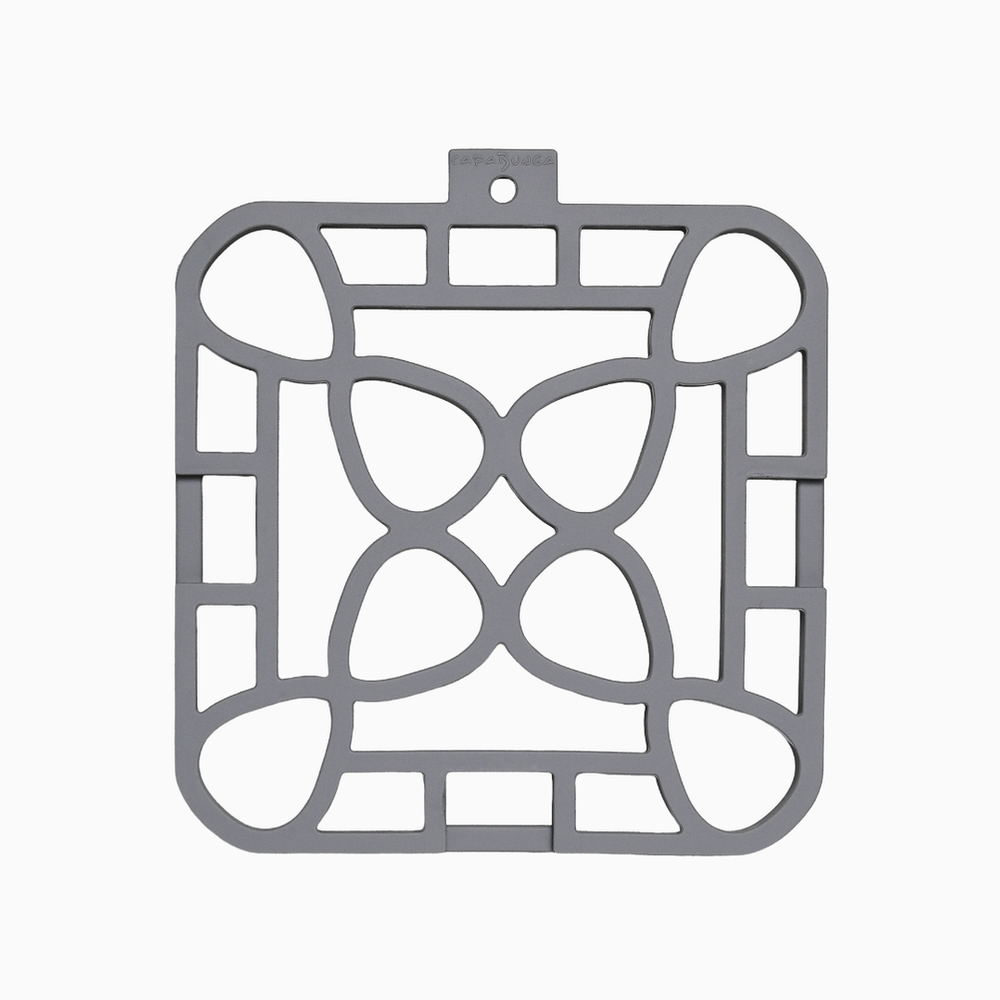 Square gray silicone trivet with geometric cutout pattern of curves and rectangles; available in multiple sizes.