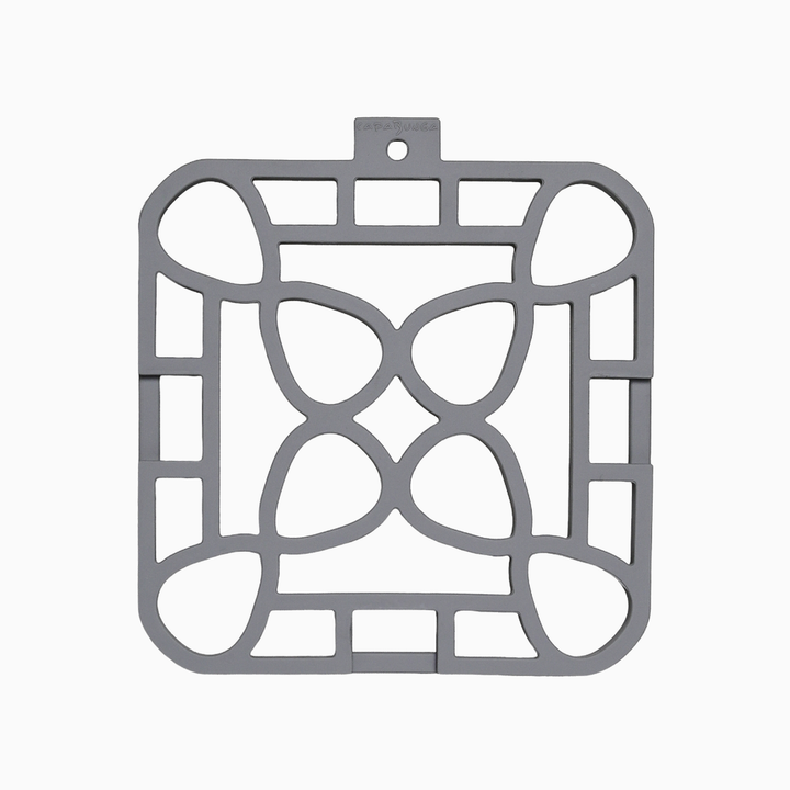 Square gray silicone trivet with geometric cutout pattern of curves and rectangles; available in multiple sizes.