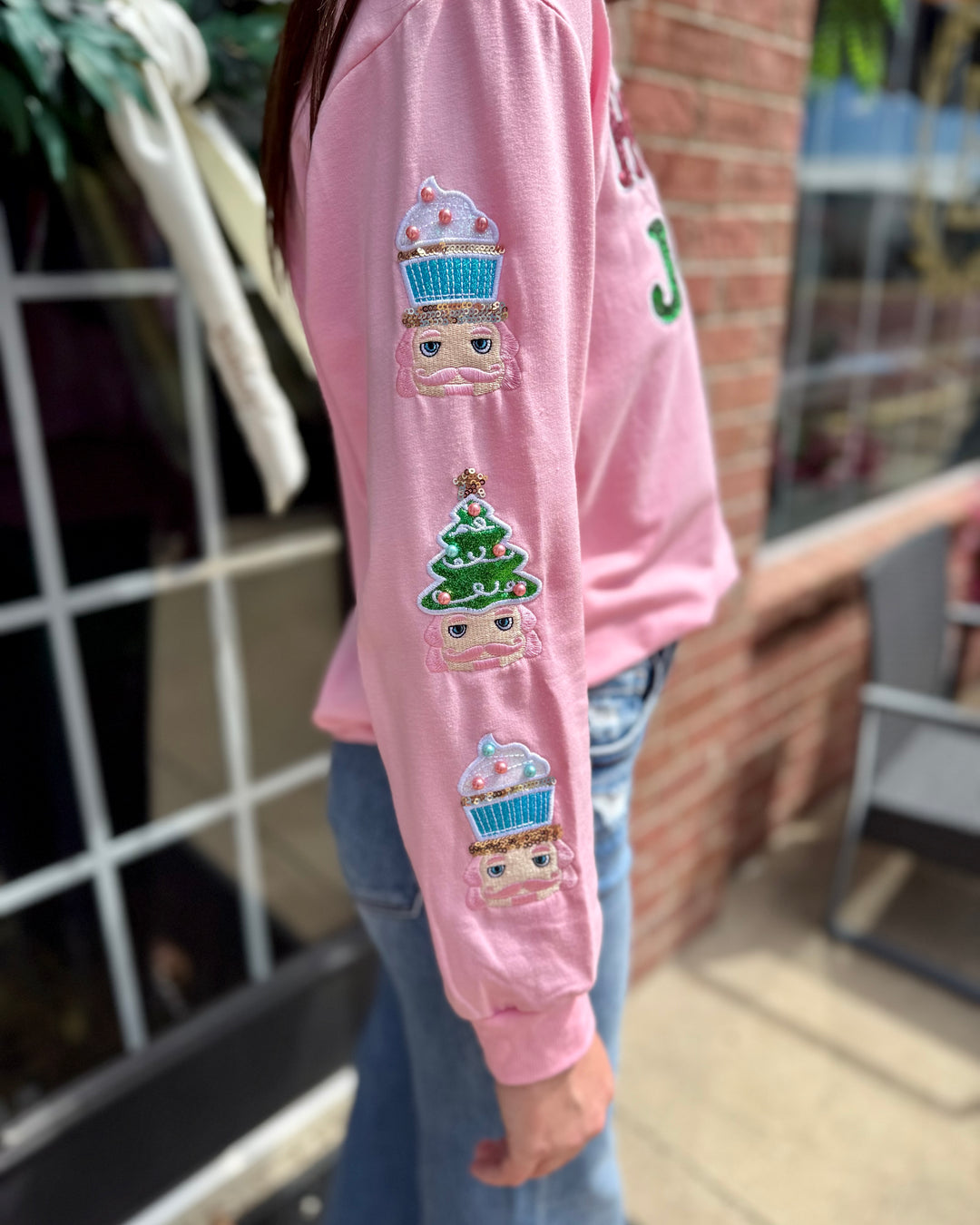 Holly Jolly Sweatshirt: pink sequin sweatshirt with embroidered cupcakes and a Christmas tree on the sleeve. Available in sizes S-XL.