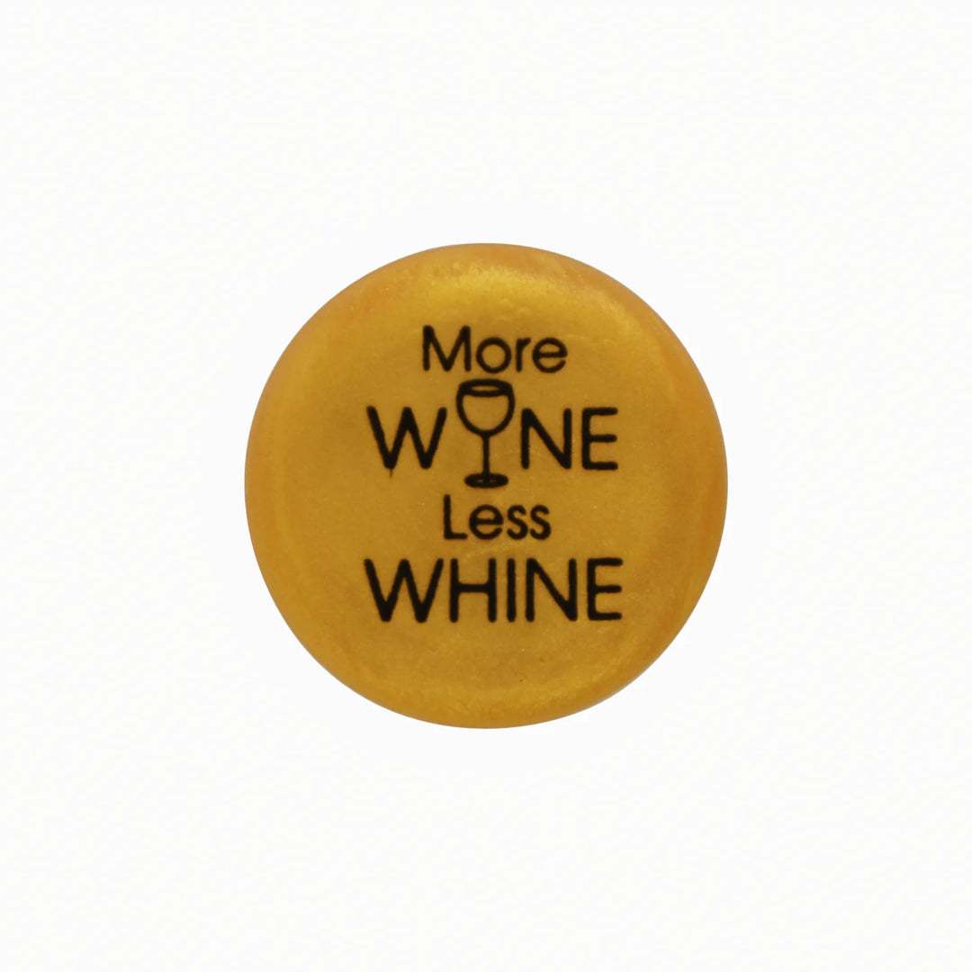 Round yellow button, "More WINE Less WHINE" text, wine glass icon as "I." Available in multiple sizes.