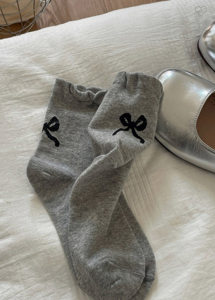 This product is a pair of grey mid-calf socks featuring cute frowning face designs. The socks are only available in one size designed to fit most adults. The product does not include a white bedsheet or metallic silver shoe.