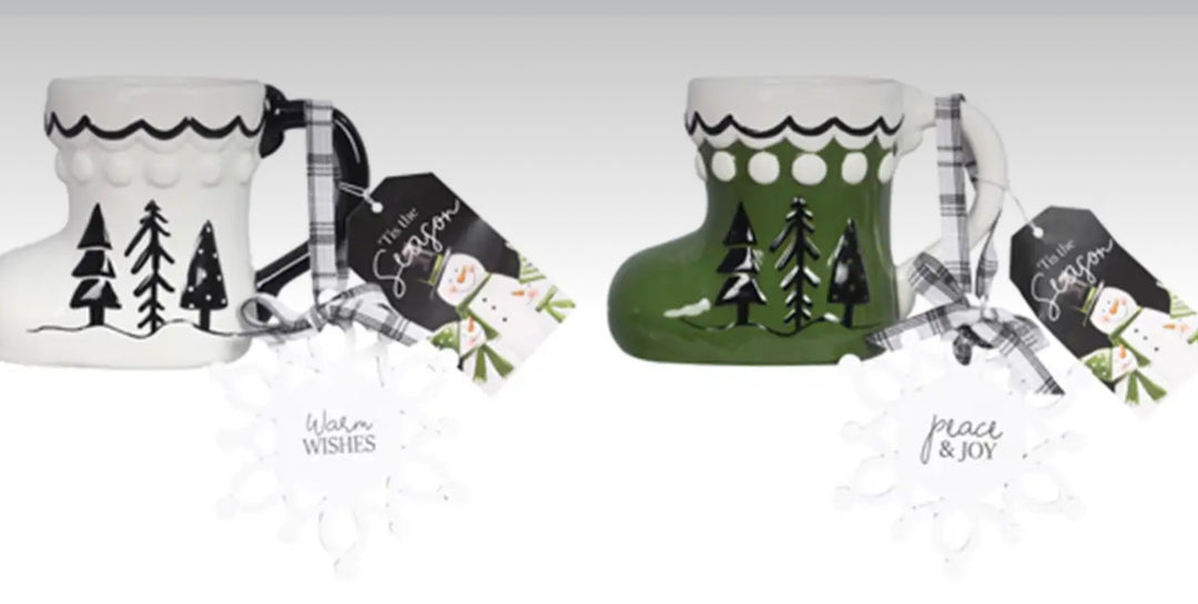 Two Ceramic Twas the Night boot-shaped mugs, one white and one green, featuring tree illustrations, plaid ribbon handles, and gift tags.