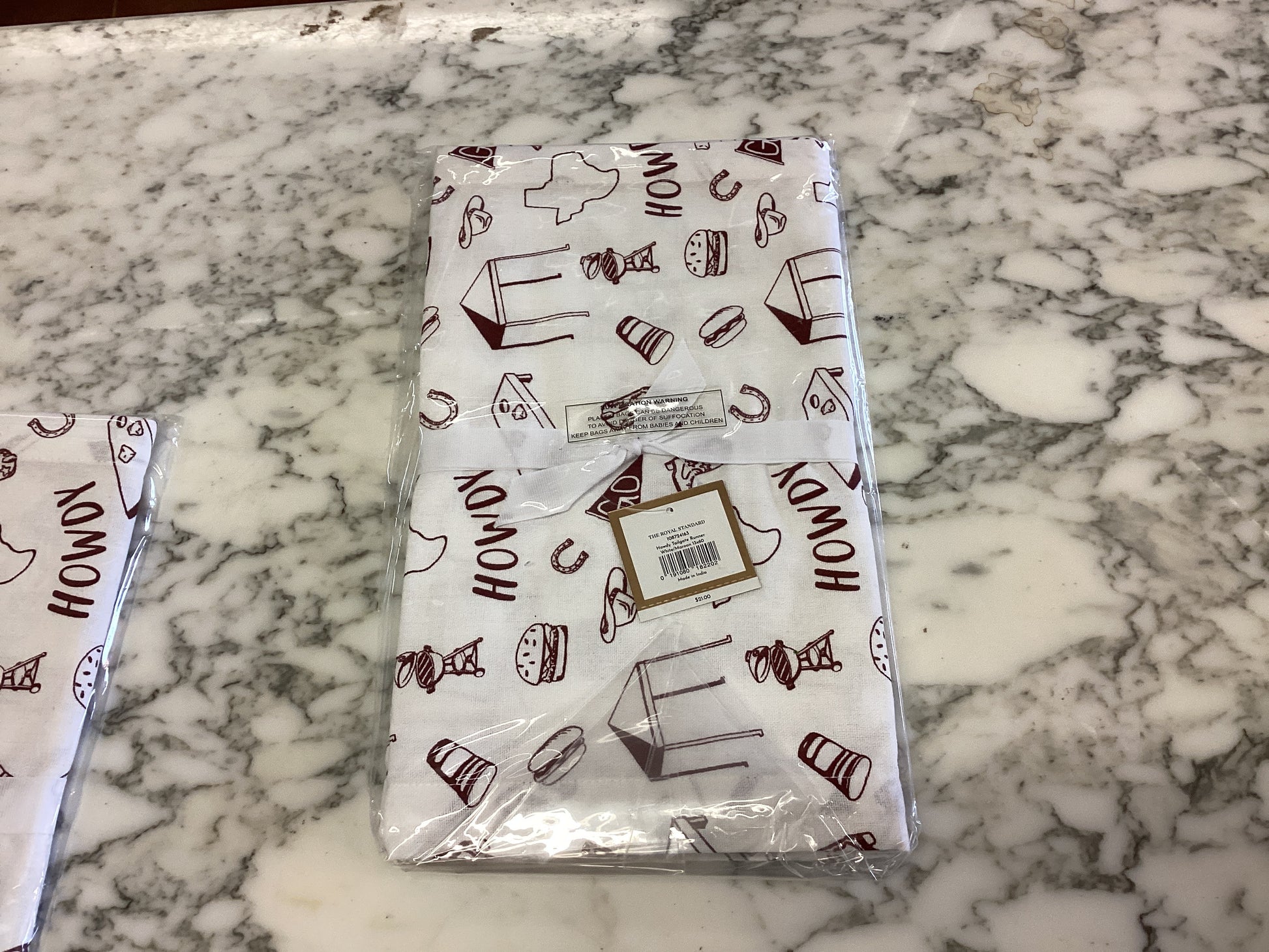 White and maroon "HOWDY" tailgate table runner, Western style, folded in clear plastic. Sizes available: 72", 90".
