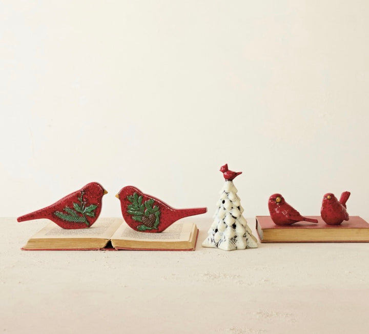 Two hand-painted embossed ceramic bird figurines in red and yellow, decorated with pine branches and pinecones.