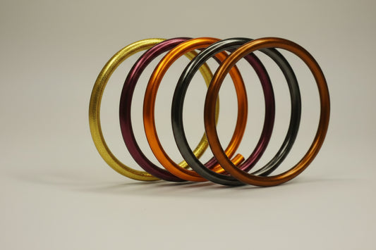 Five metallic The Autumn AWS Stack Bangles by BuDhaGirl in gold, purple, orange, and black. Available in multiple sizes.