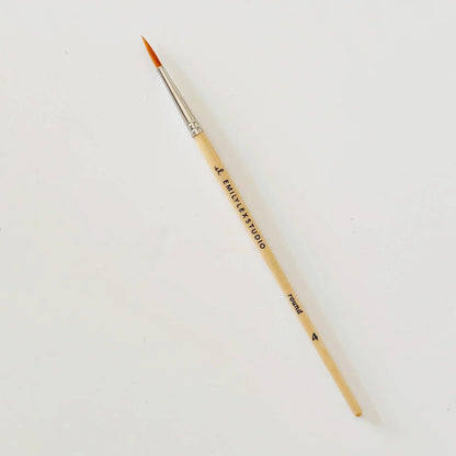 Thin paintbrush with wood handle and fine orange synthetic taklon bristles; available in multiple sizes.