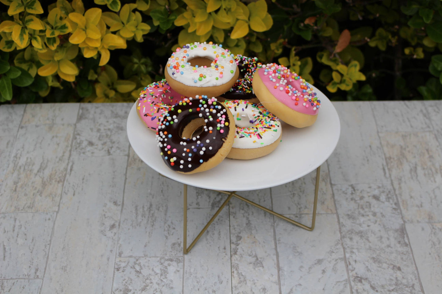 Assorted Fake Donuts on a White Plate. Designed as decorative donuts with colorful sprinkles. Ideal as aesthetic outdoor table decor. Only available in one standard size.